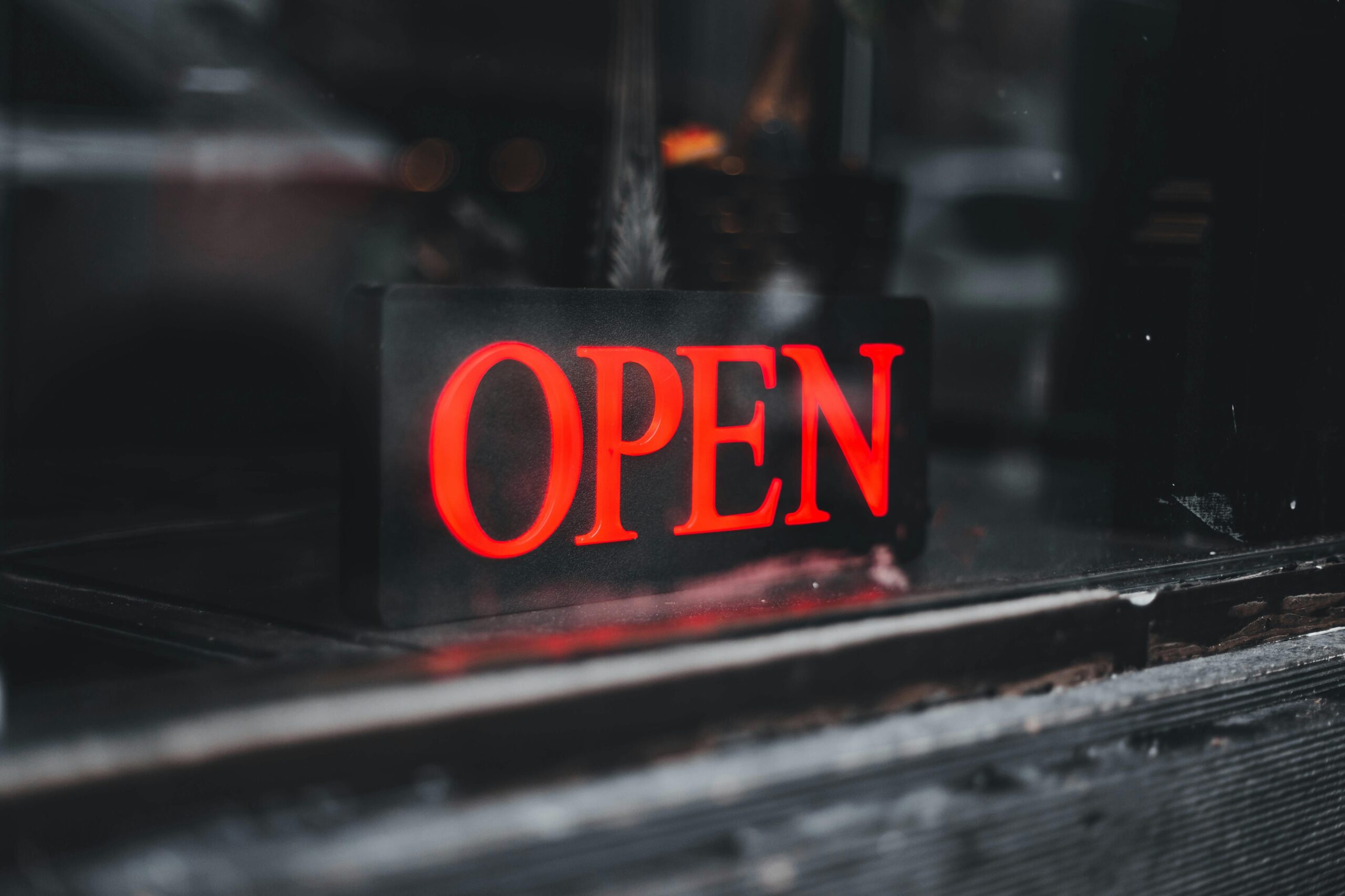 About Vibrant red neon open sign in a storefront window, inviting customers.