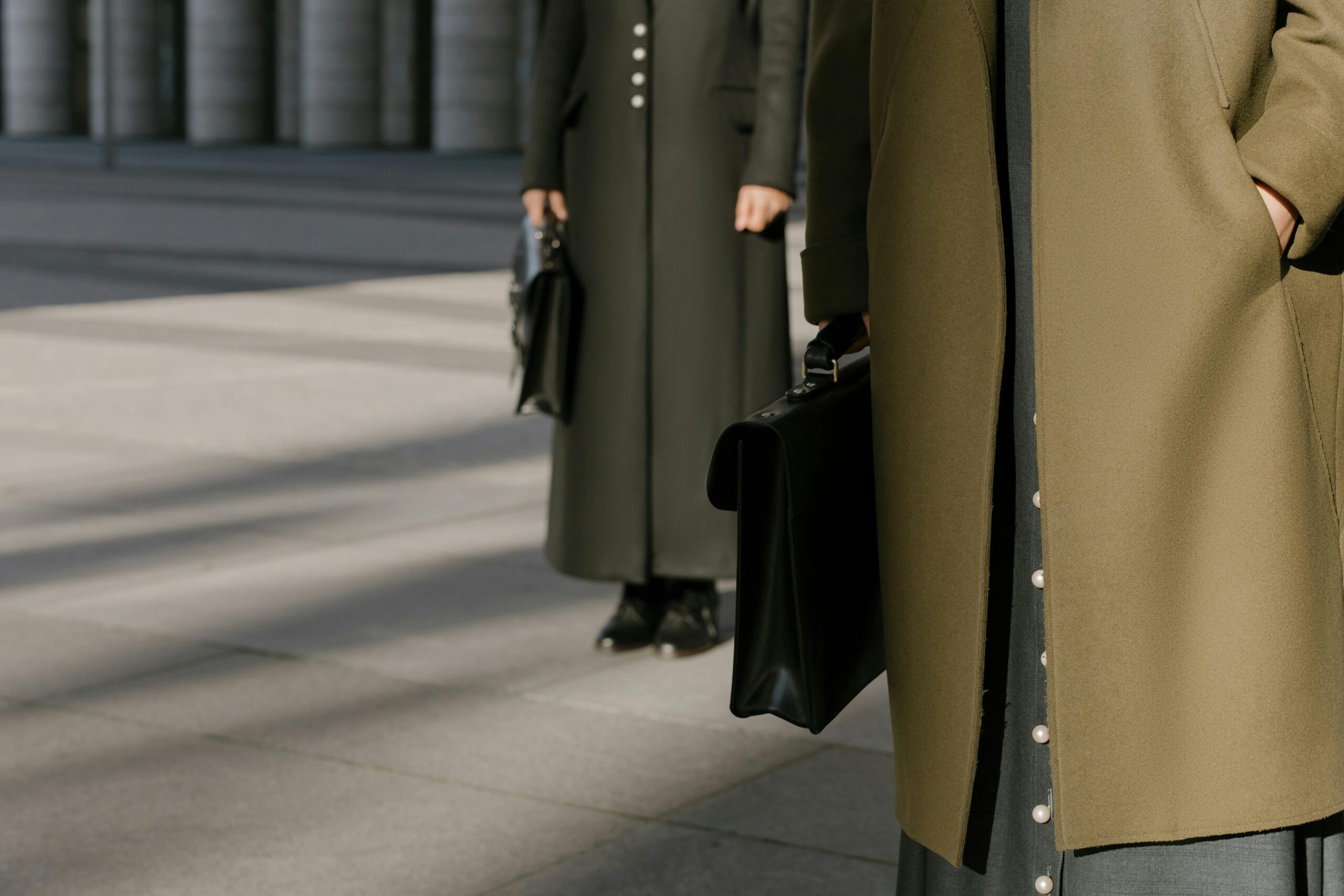 About Close-up of two professionals holding briefcases in stylish coats on the pavement.