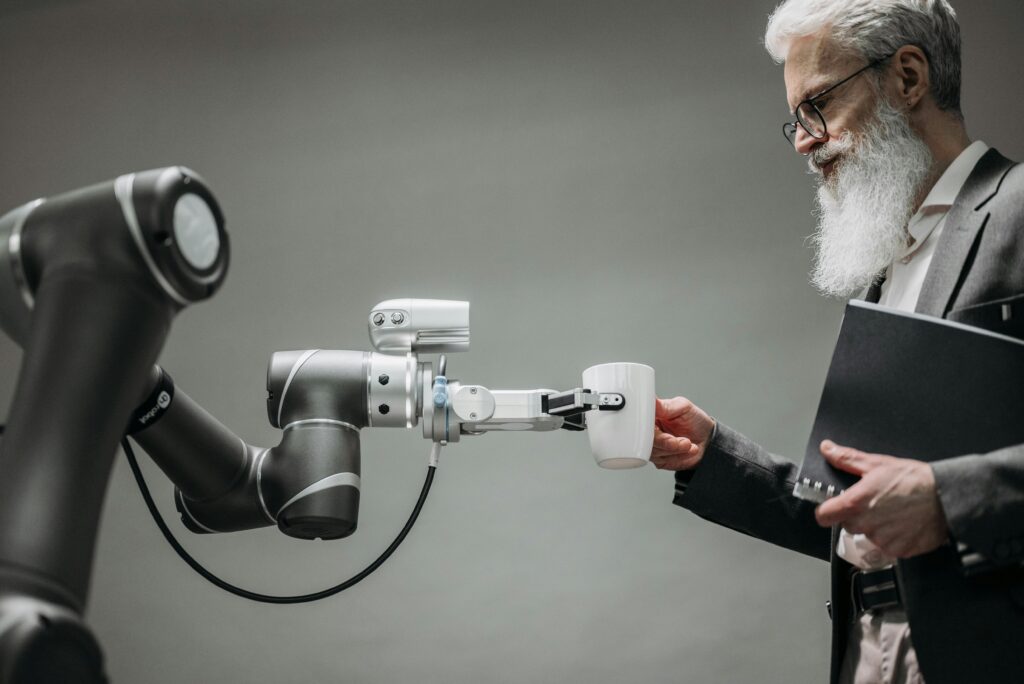 Les métiers de l’informatique les plus demandés en Algérie en 2025 An elderly man receives a cup from a robotic arm in a modern office setting.